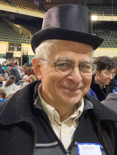 Man wearing top hat and wireframe glasses smiles at the camera