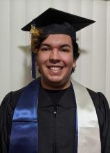 Man wearing a graduation cap smiles before a white background