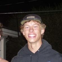 Man with a black baseball hat smiling at the camera.